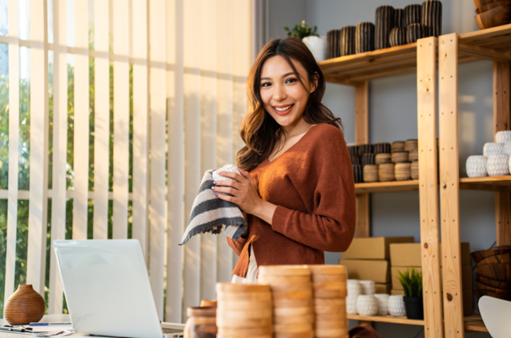 Portrait of Asian young woman learning what is fundability while she packs order into box and looks at camera